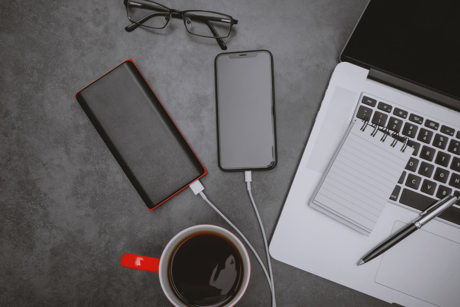 Laptop, Mobile Phone Charging With Power Bank and Coffee Mug on Work Desk